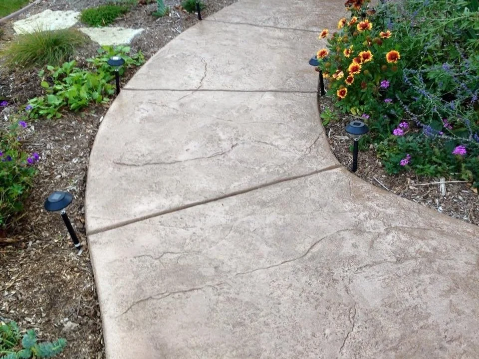 Stamped decorative concrete walkway through a landscaped bed